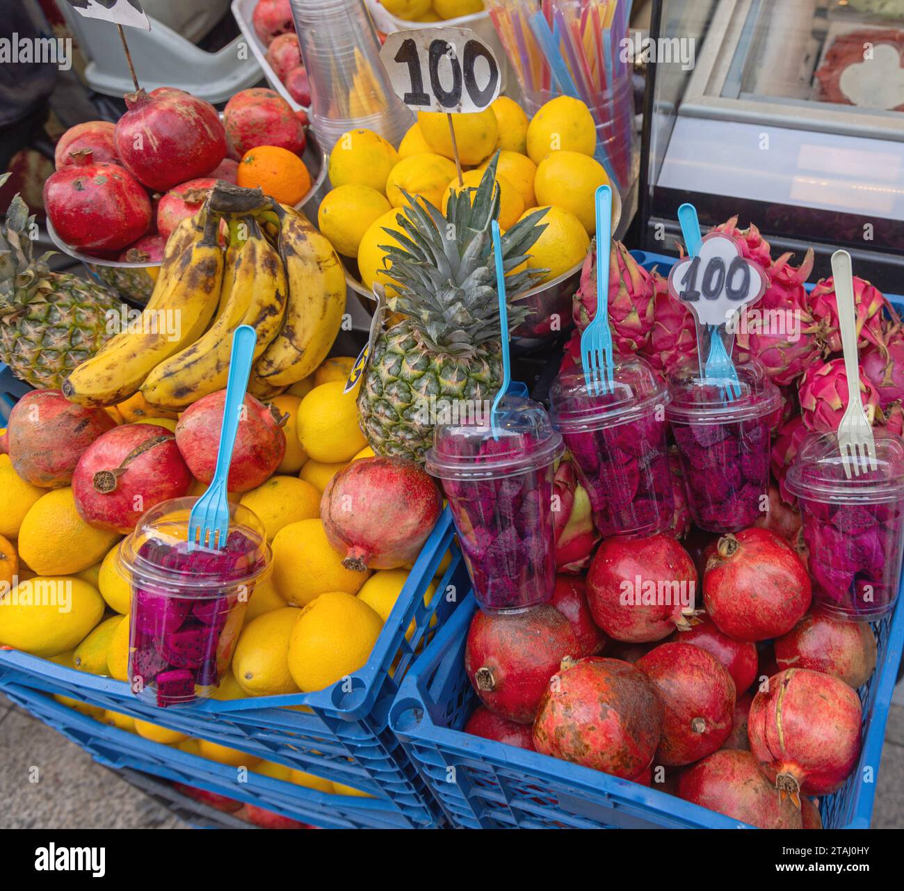 Stücke lila Drachenfrucht in Bechern, die verzehrfertig sind, und Früchte in Kisten mischen Stockfoto