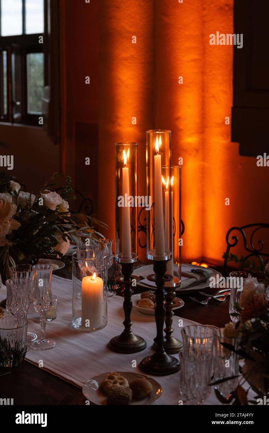 Kerzenlicht und sanfte Beleuchtung sorgen für eine warme und romantische Atmosphäre im Bankettsaal für eine große italienische Hochzeit. Stockfoto