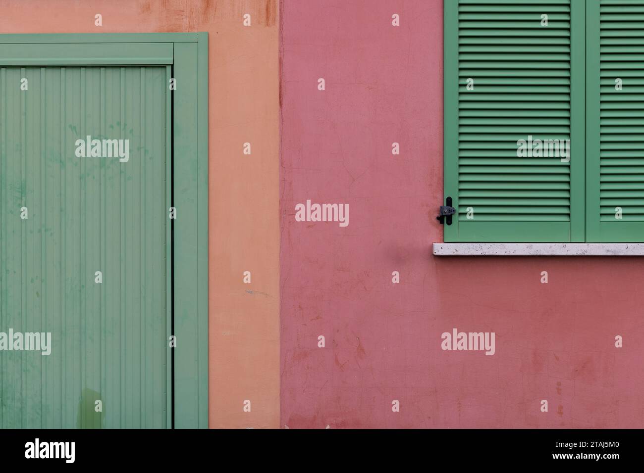 Ein Außenbereich eines italienischen Apartmentgebäudes, kunstvoll in Grün, Orange und Rosa gestrichen. Stockfoto