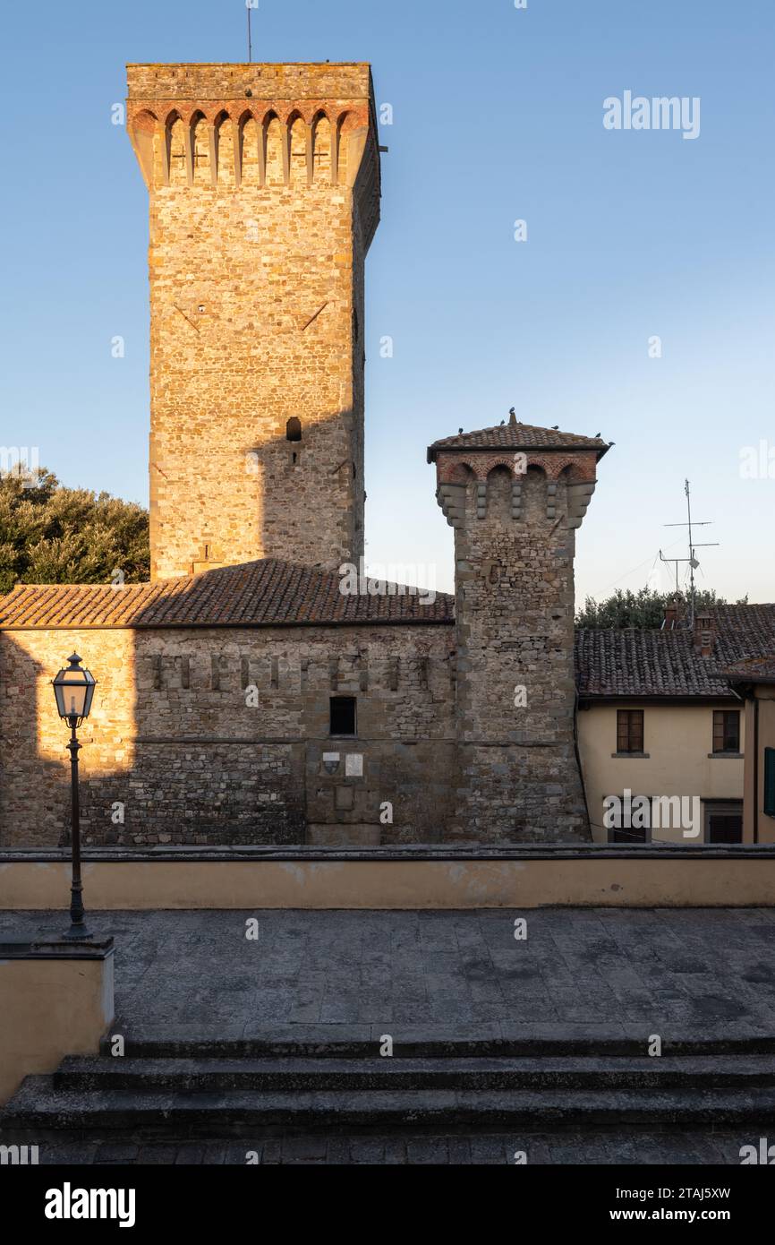 Die ersten Sonnenstrahlen am frühen Morgen treffen auf die alte Ziegelfassade von Gebäuden in Lucignano, Toskana, Italien. Stockfoto