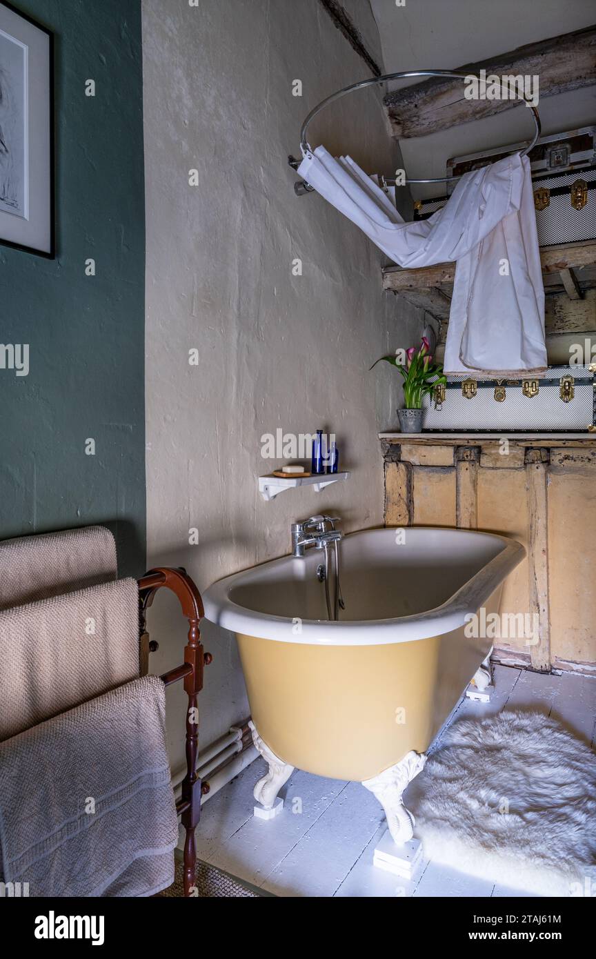 Freistehende Badewanne mit Duschvorhang in georgianischer Scheune, Tetbury, Gloucestershire, Großbritannien. Stockfoto