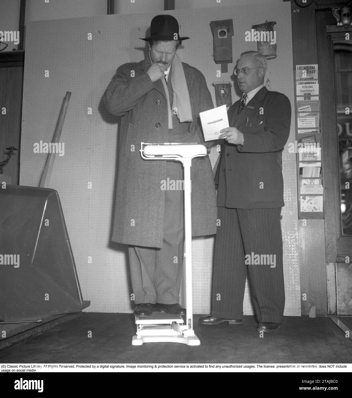 Auf der Waage in den 1940er Jahren Schauspieler Åke Fridell sieht nachdenklich aus, wenn er auf der Waage steht, vielleicht ist sein Gewicht nicht das, was er dachte. Schweden 1949. Foto Kristoffersson Ref. AN83-1 Stockfoto