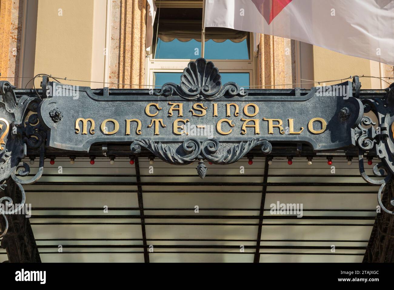 Schild oberhalb des Haupteingangs von Monte Carlo/Monte-Carlo Casino, Monaco. Eine Flagge fliegt in der Sommerbrise. (135) Stockfoto