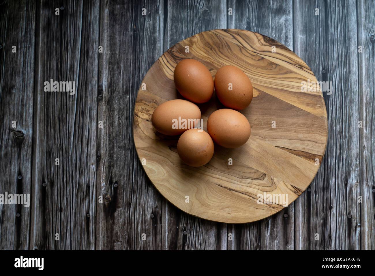 Eier auf Holzteller, rohe Zutaten Stockfoto