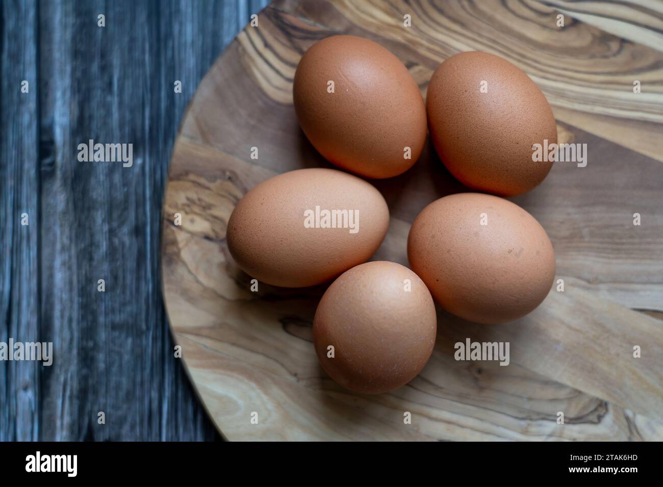 Eier auf Holzteller, rohe Zutaten Stockfoto