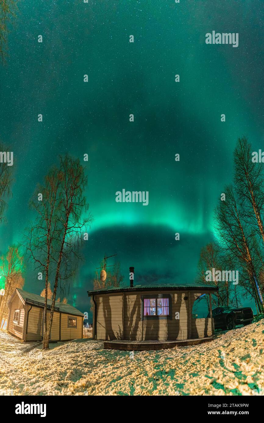 Vertikales Nachtfoto von wunderschönen Nordlichtern über einem kleinen hölzernen Berghaus in Nordschweden, Lappland, Joesjo. Grünes Licht von Aurora Bore Stockfoto