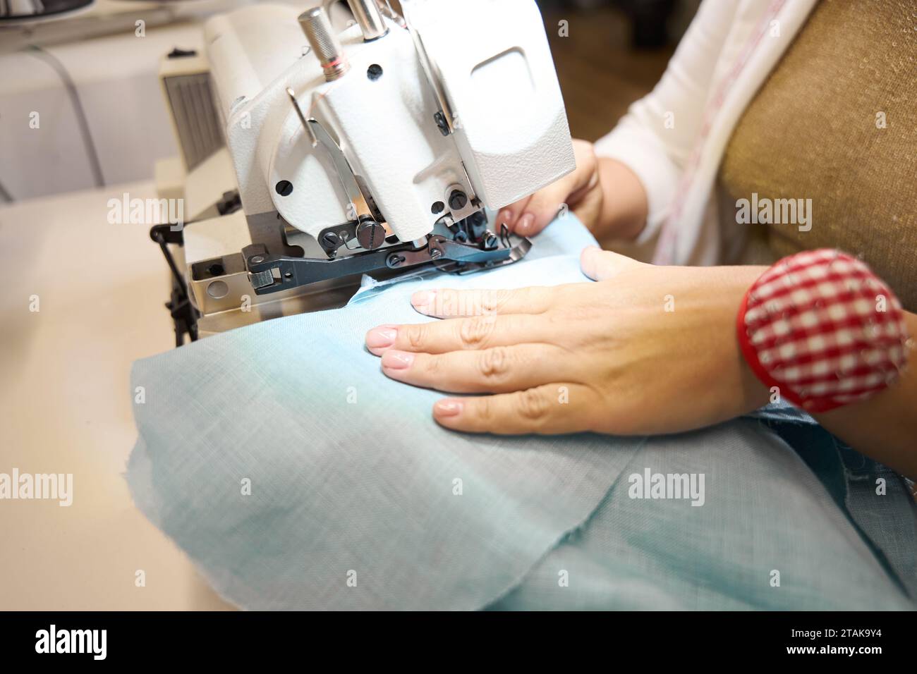 Die Schneiderin arbeitet an einer Nähmaschine mit blauem Stoff Stockfoto