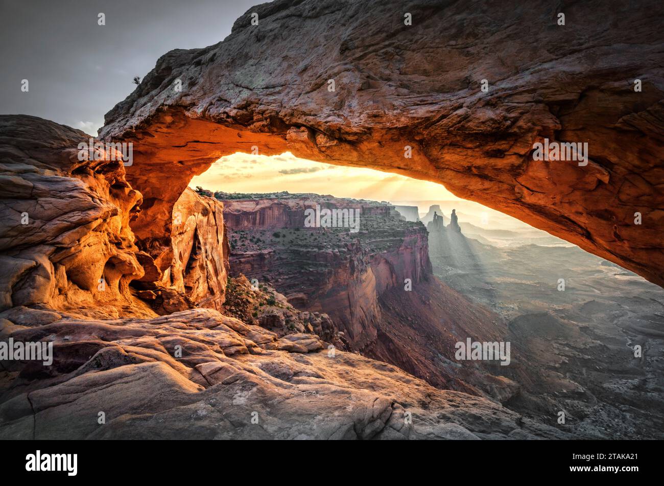 Mesa Arch, ein Wahrzeichen der Canyonlands, umrahmt den Sonnenaufgang in seiner natürlichen Umgebung und bietet spektakuläre Ausblicke durch die majestätische Felsöffnung. Stockfoto