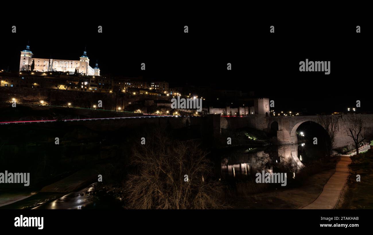 Lange Exposition der Alcantara-Brücke, einem historischen Bau über dem Tejo und dem Real Alcazar bei Nacht, in der Stadt Toledo, Spai Stockfoto