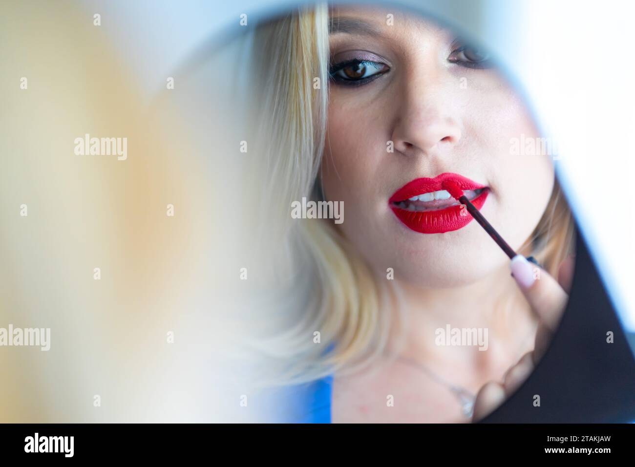 Nahporträt einer jungen Frau, die roten Lippenstift auf die Lippen legt Stockfoto