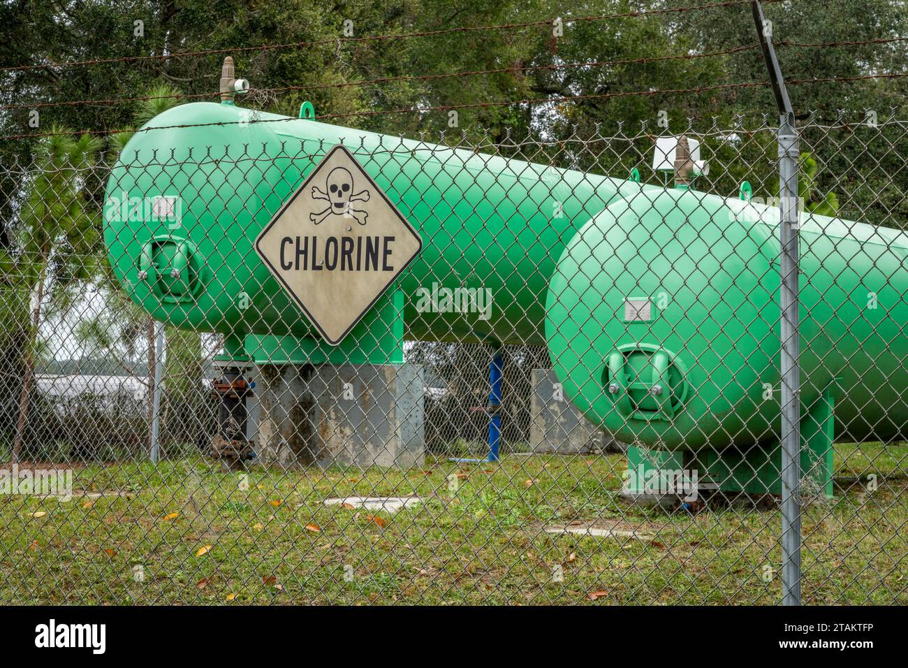 Industrielle Chlorgastanks hinter einem Zaun mit Warnschild Stockfoto