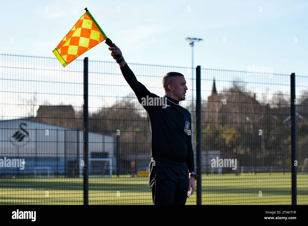 Swansea, Wales. 1. Dezember 2023. Der stellvertretende Schiedsrichter Adam Gregory hisst seine Flagge für einen Einwurf während des U21 Professional Development League-Spiels zwischen Swansea City und Colchester United an der Swansea City Academy in Swansea, Wales, Großbritannien am 1. Dezember 2023. Quelle: Duncan Thomas/Majestic Media/Alamy Live News. Stockfoto