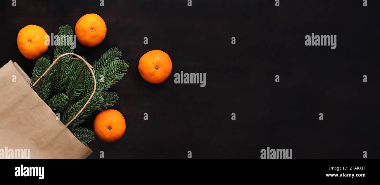Ein Fichtenzweig in einem Bastelbeutel, reife Mandarinen, ein Blick von oben auf die Gegenstände auf dem Tisch. Weihnachtskomposition, Neujahr. Kaufen Sie einen kleinen Weihnachtsbaum oder Stockfoto