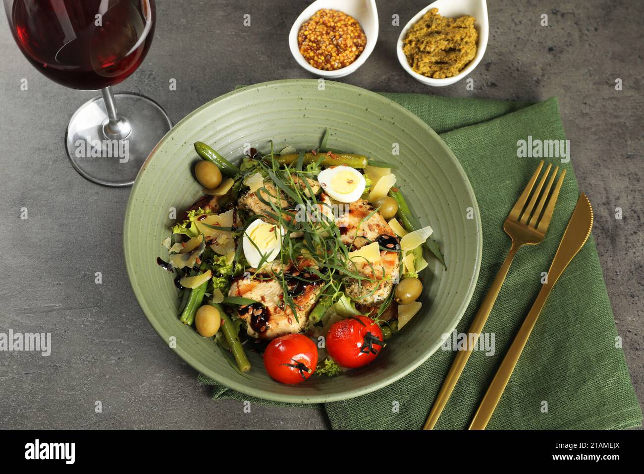 Leckeres Gericht mit Estragon, Salatdressings und einem Glas Wein, serviert auf grauem Tisch, über der Aussicht Stockfoto