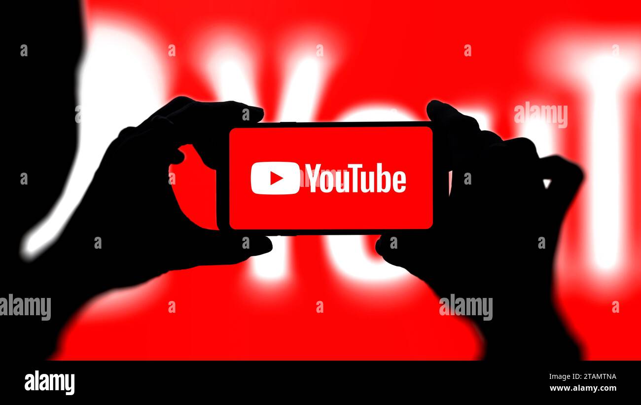 YouTube-Logo auf Smartphone mit rotem Hintergrund. Frau, die mit dem youtube-Logo ein Foto macht oder filmt. Stockfoto