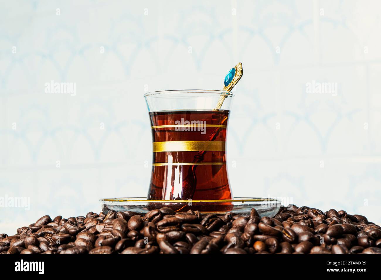 Schwarzer, köstlicher Kaffee in einem Glasbecher, Glas und verstreute Körner auf dem Tisch. Authentisches Getränk, Kopierraum. Stockfoto