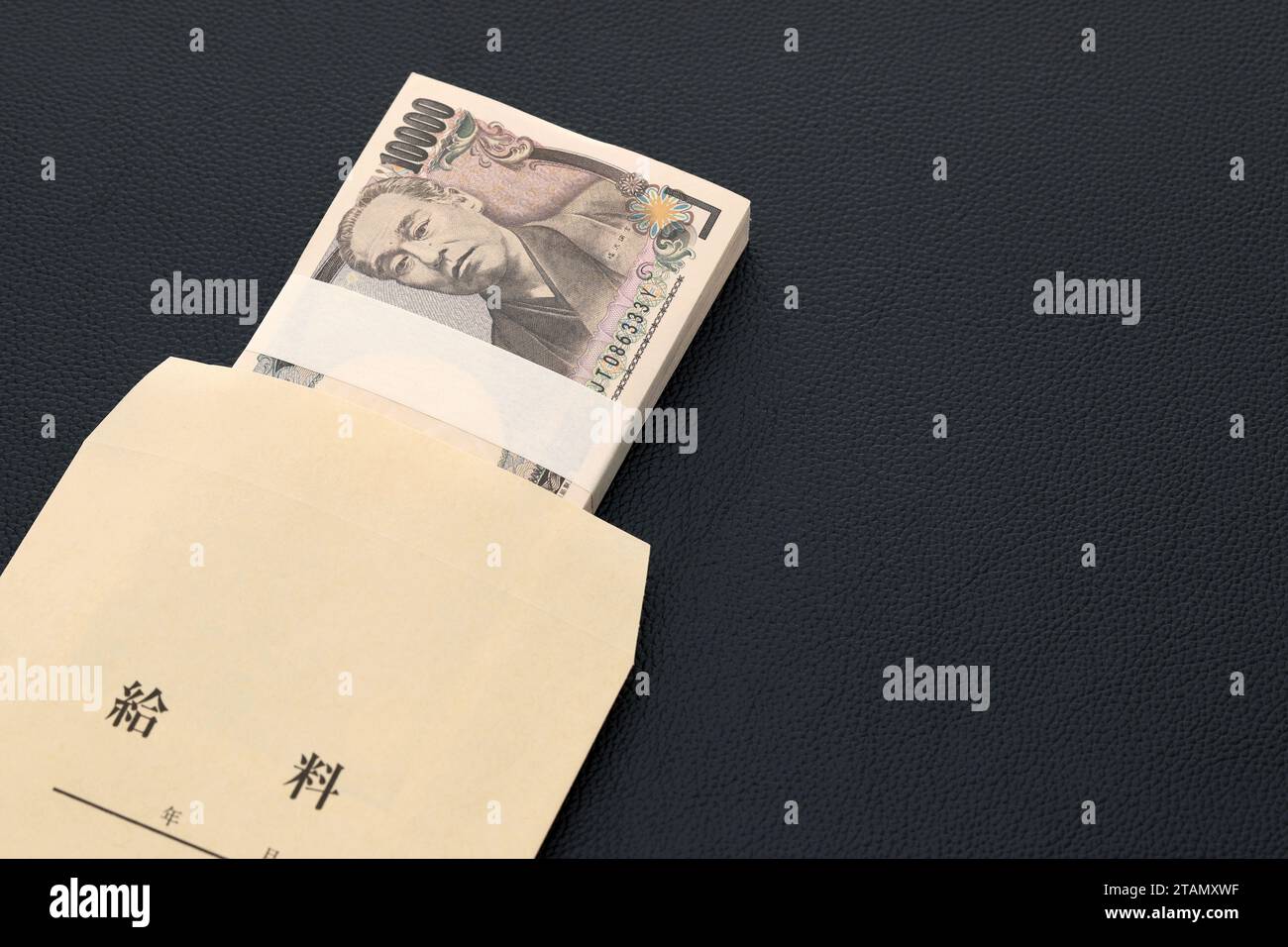 Japanisch zehntausend Yen auf einem Gehaltsbeutel auf schwarzem Hintergrund, Übersetzung: Gehalt, Jahr, Monat, Tag. Stockfoto