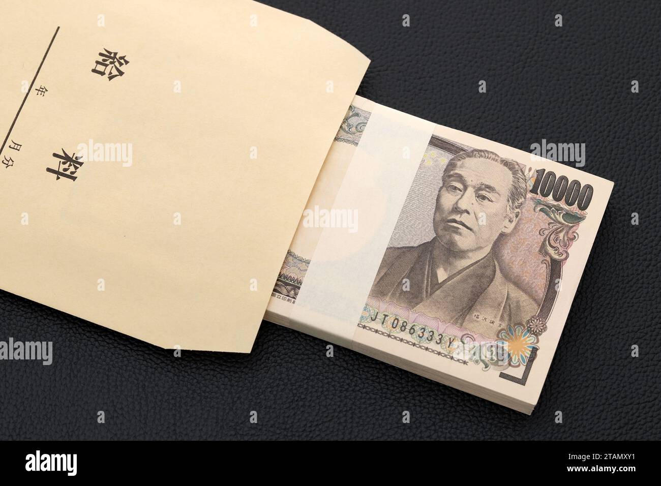 Japanisch zehntausend Yen auf einem Gehaltsbeutel auf schwarzem Hintergrund, Übersetzung: Gehalt, Jahr, Monat, Tag. Stockfoto