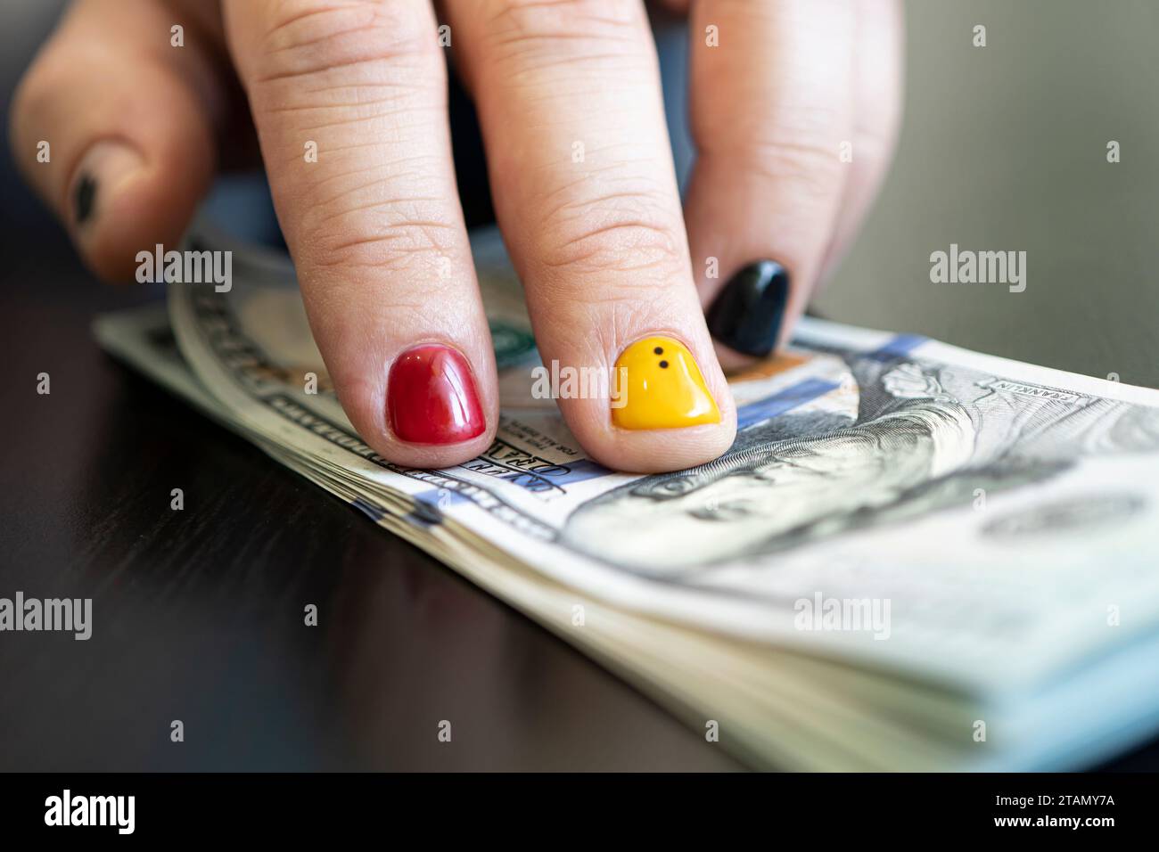 Hände, die Dollarscheine auf einem Holztisch zählen. Der metrosexuelle Typ zählt das Geld. Design für Männernägel. Stockfoto