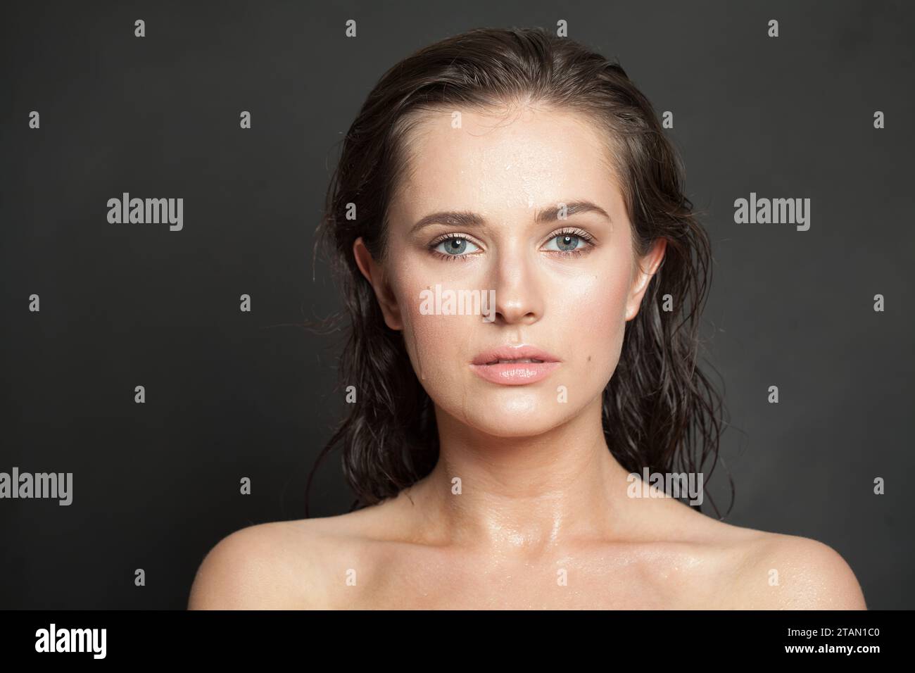 Schönes weibliches Modell mit gesunder frischer nasser Haut und dunklem Haar in die Kamera schauen, Mode Schönheit Porträt Stockfoto