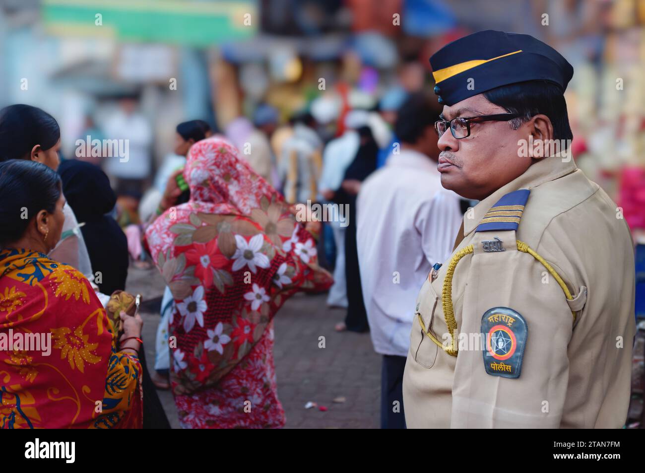 Ein Polizist wacht über die Menge, die Mira Datar Dargah in Darukhana, Byculla, Mumbai, Indien, besucht, einem muslimischen Schrein, in dem sich das Grab eines muslimischen heiligen befindet Stockfoto
