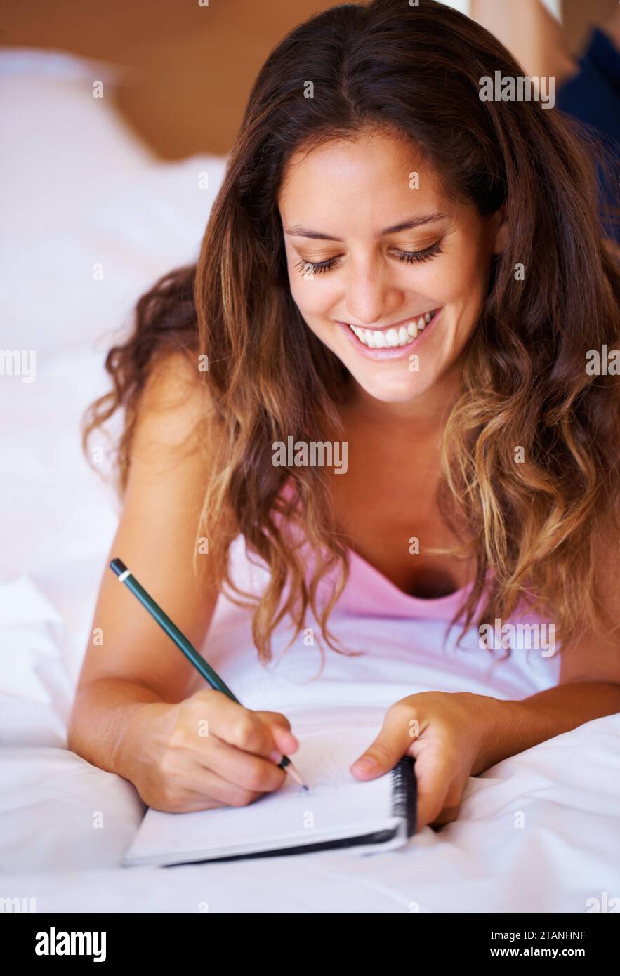 Studentin, Lächeln und Schreiben zum Studium im Schlafzimmer mit Notizen, Idee und Planung im Buch. Jung, Frau und Freude im Gesicht für Journale, Tore oder Stockfoto