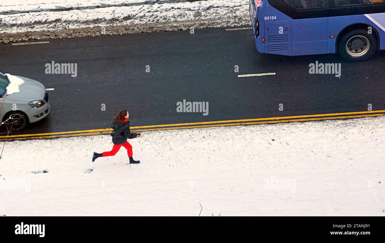 Glasgow, Schottland, Großbritannien. Dezember 2023. Wetter in Großbritannien: Es war über Nacht eiskalt und sah einen Schneefall über dem West End Vorort von Ritghtswood in der Stadt, als die Einheimischen zu einer Weihnachtsszene aufwachten und ein Kind für den Bus rennte. Credit Gerard Ferry/Alamy Live News Stockfoto