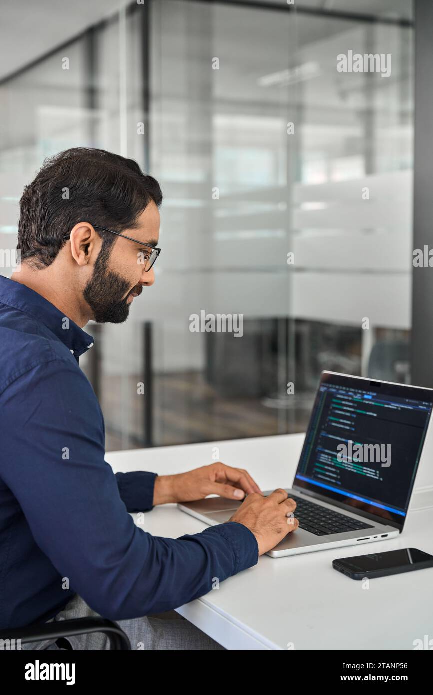 Indischer Geschäftsmann Softwareentwickler, der im Büro an einem Laptop arbeitet. Vertikal Stockfoto