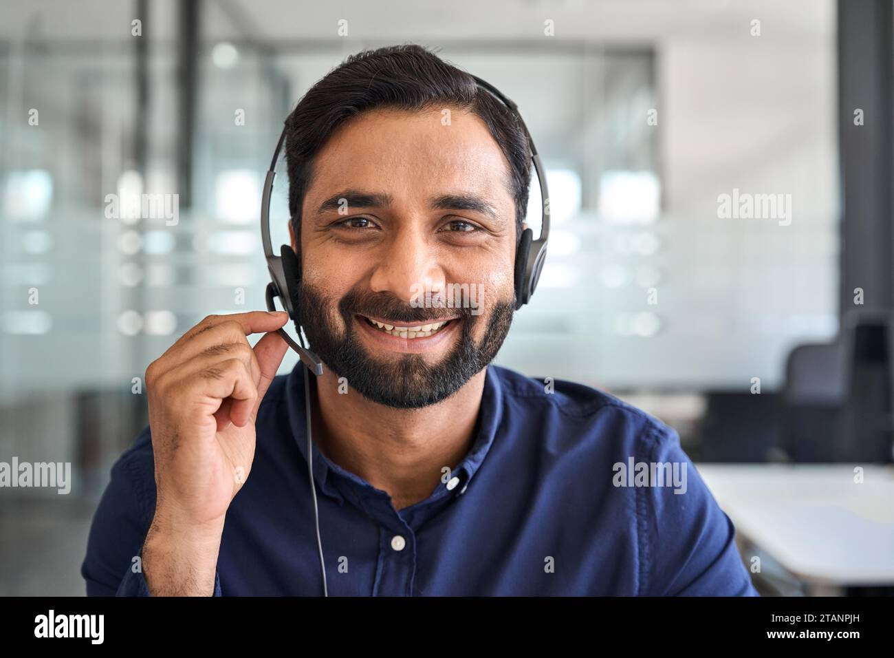 Lächelnder Indianer Callcenter-Agent, der im Büro ein Headset trägt, Porträt. Stockfoto