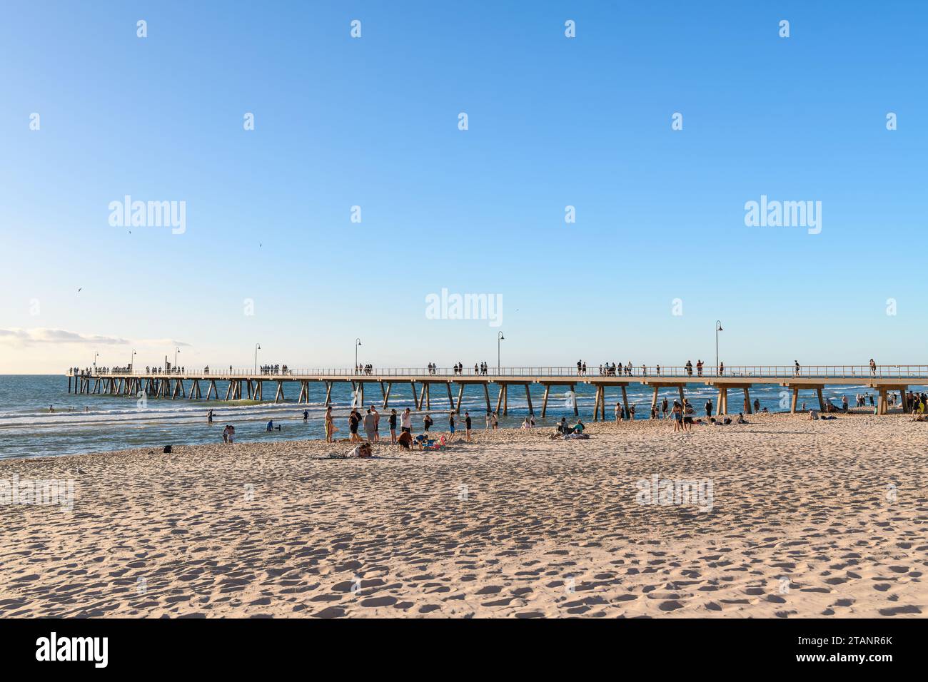 Adelaide, Südaustralien - 2. Januar 2023: Glenelg Beach strahlt hell, während die Menschen die Sonne auf dem goldenen Sand genießen, mit Blick auf den Bootssteg Stockfoto