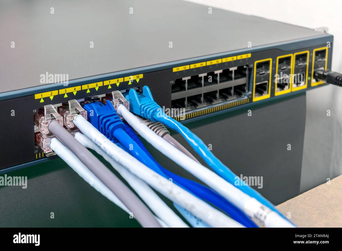 Netzwerk Gigabit Smart PoE Switch mit angeschlossenen Netzwerkkabeln wird am Schreibtisch getestet Stockfoto