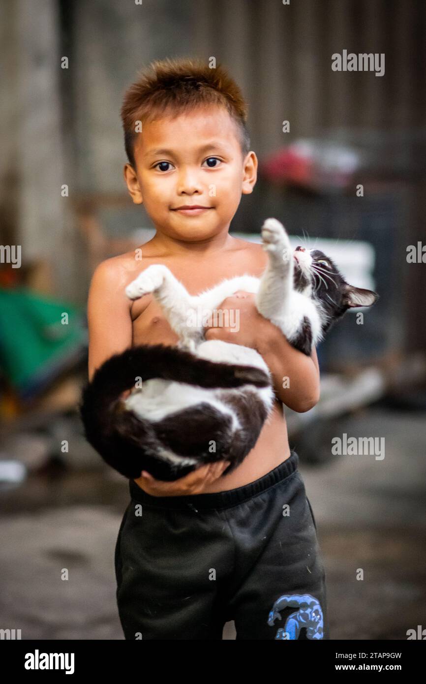 Ein süßer, junger philippinischer Junge hält seine Katze in Manila auf den Philippinen. Stockfoto