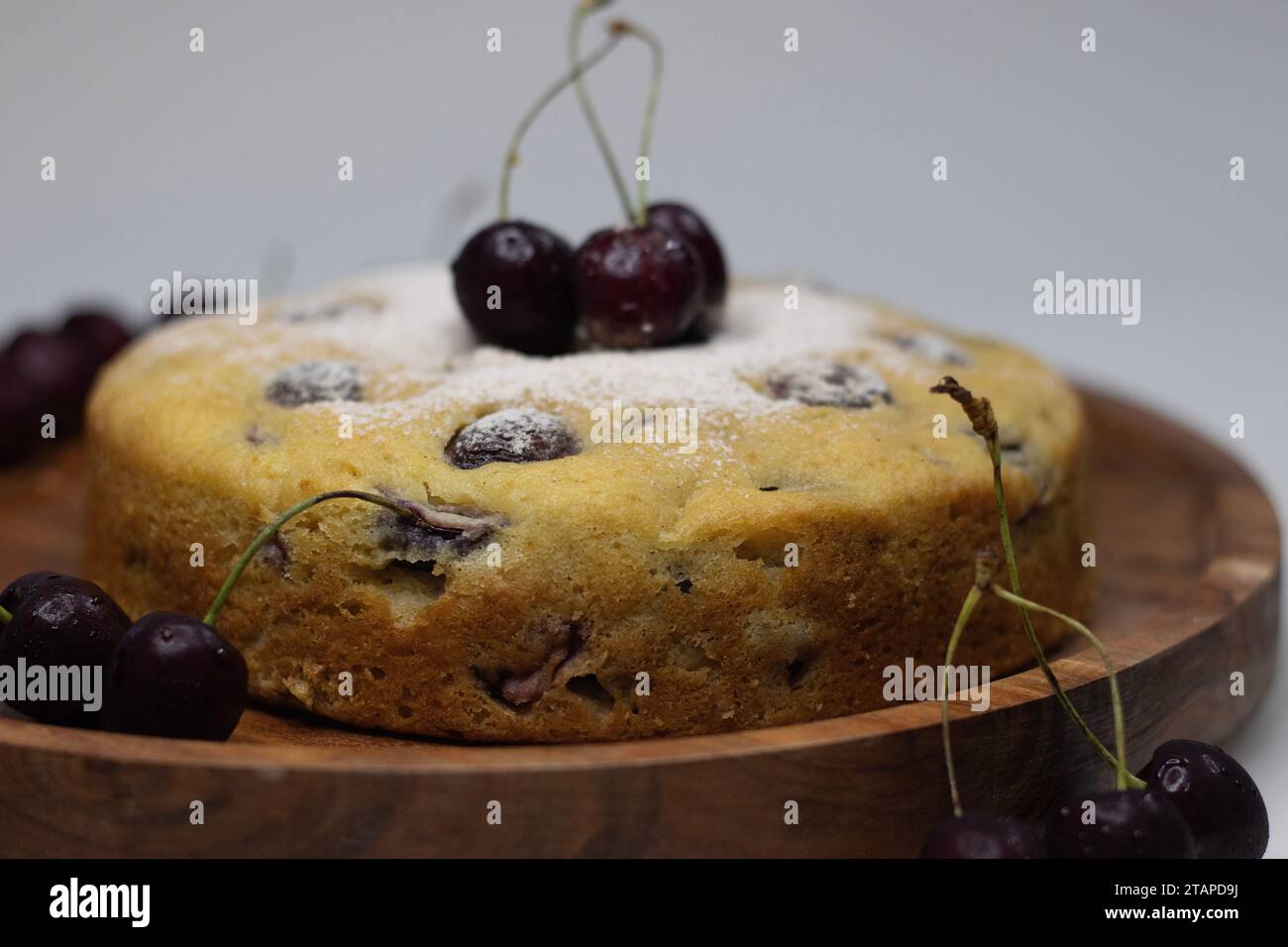 Kirschjoghurtkuchen. Köstlicher Joghurtkuchen mit frischen Kirschen, ein feuchtes und fruchtiges Dessert, perfekt für jeden Anlass. Nahaufnahme auf weißem Rücken Stockfoto