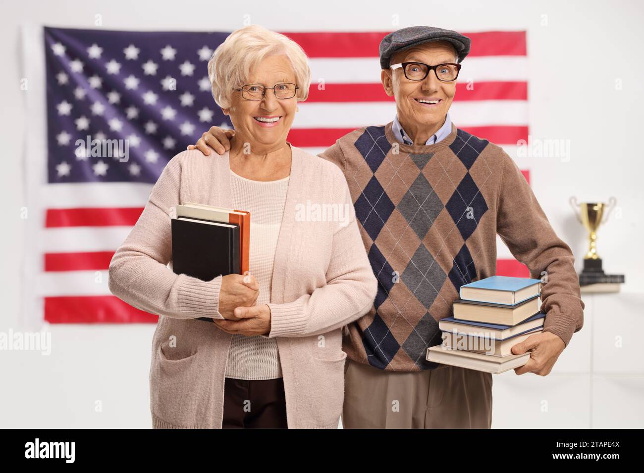 Ältere Männer und Frauen halten Bücher und posieren vor einer amerikanischen Flagge Stockfoto