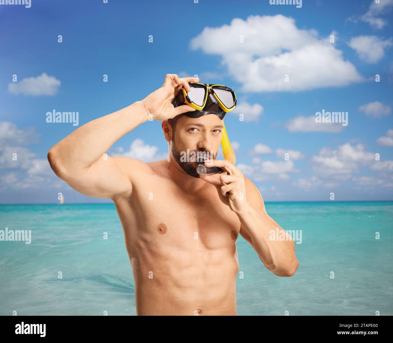 Mann, der im Meer steht und eine Tauchermaske aufsetzt Stockfoto