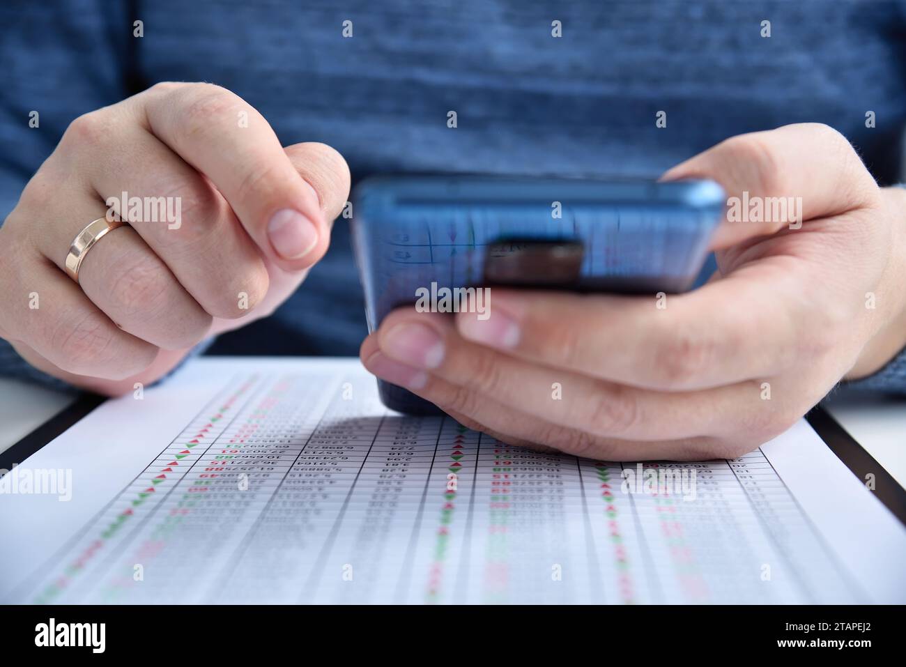 Hände, die das Smartphone und die Finanzdaten auf dem Tisch halten. Geschäfts- und Finanzkonzept. Nahaufnahme Stockfoto