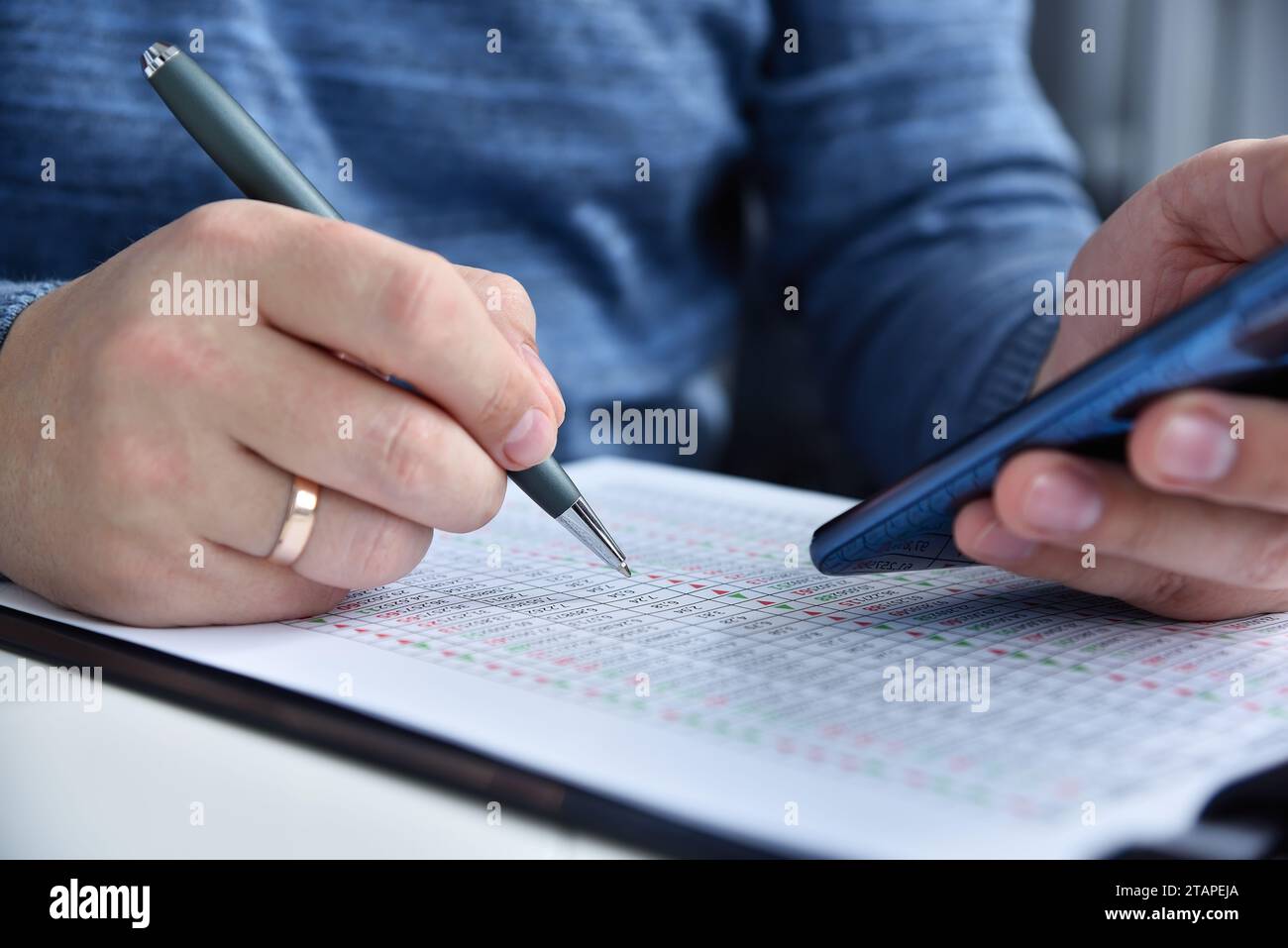 Geschäftsmann prüft Finanzberichte und vergleicht Daten auf Telefon und Papier. Internet-Handel und Geschäftskonzept. Nahaufnahme Stockfoto