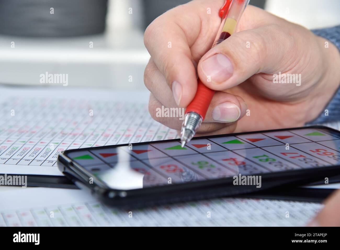 Händler-Mann prüft den Finanzbericht und vergleicht Daten am Telefon. Internet-Handel und Geschäftskonzept. Nahaufnahme Stockfoto