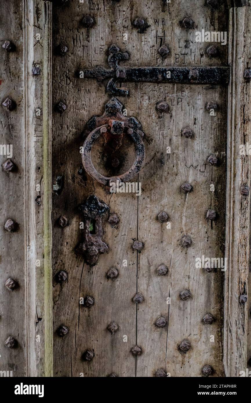 Mittelalterliche Tür mit verwittertem Holz und verrostetem Türgriff, Schlüsselloch und Scharnier Stockfoto
