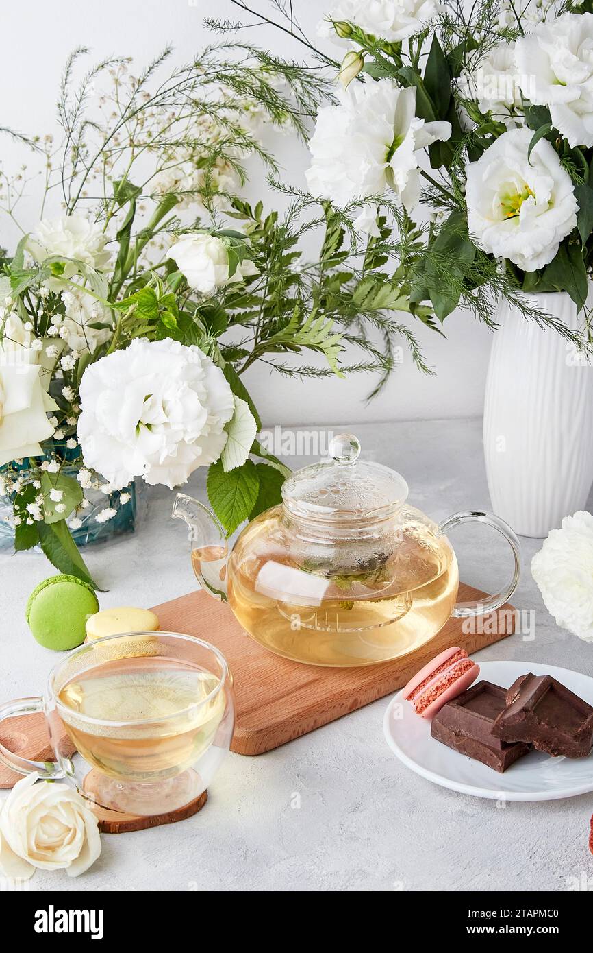 Ästhetischer Tisch - Teekanne, Tasse, Desserts, weiße Blumen - Zeit für sich, gemütliches Hauskonzept Stockfoto