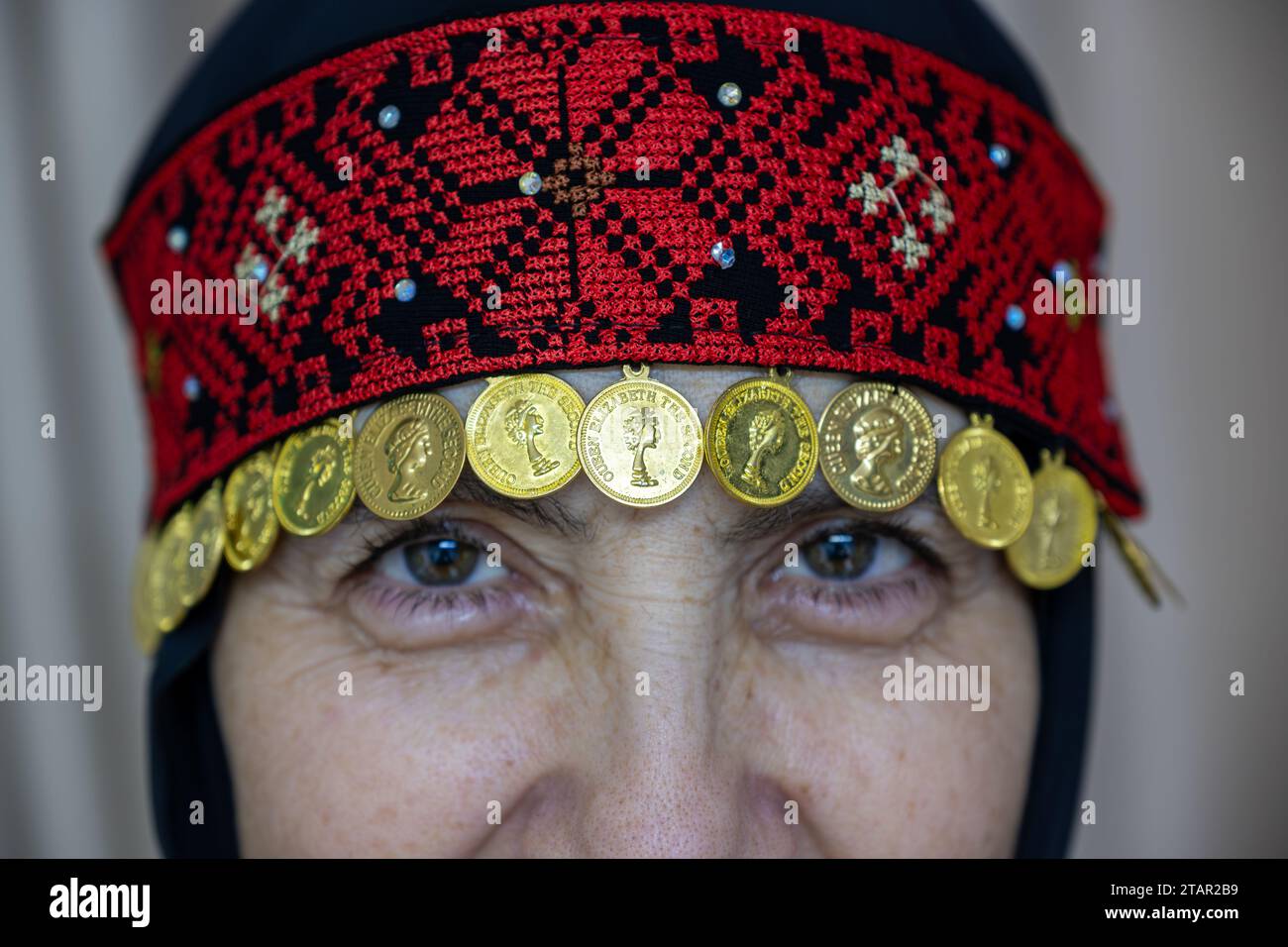 Ein palästinensisches Frauenkleid in Rot und Schwarz mit goldenen Accessoires Stockfoto