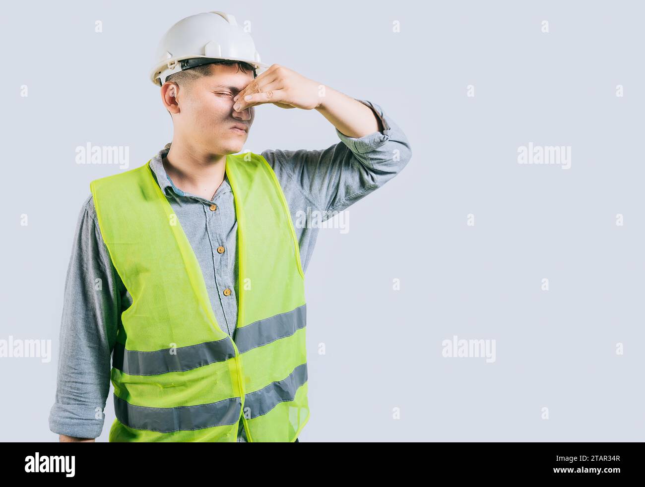 Mann Ingenieur bedeckt ihre Nase vor einem schlechten Geruch isoliert isoliert. Verärgerter junger Ingenieur, der ihre Nase isoliert hält Stockfoto