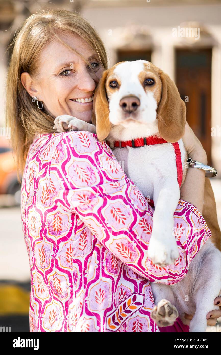 Weibliche umarmte freundliche Beagle-Hündin, die glückliche Momente genießt, während beide in die Kamera schauen Stockfoto