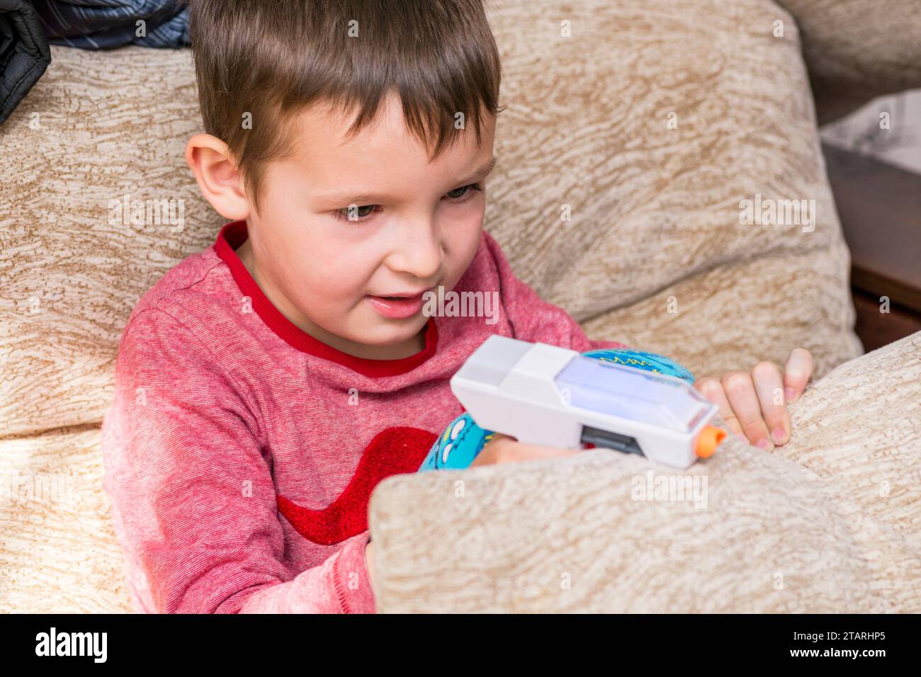 Der süße Junge spielt zu Hause mit Spielzeugpistolen Stockfoto