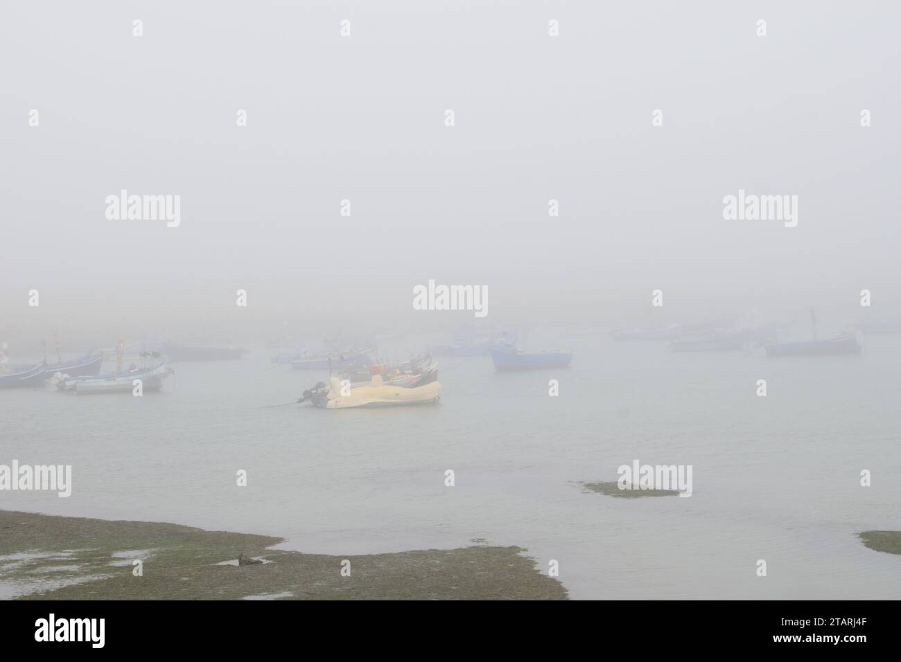 Unbearbeitetes Foto von Fischerbooten in einem Hafen bei nebeligem Wetter Stockfoto