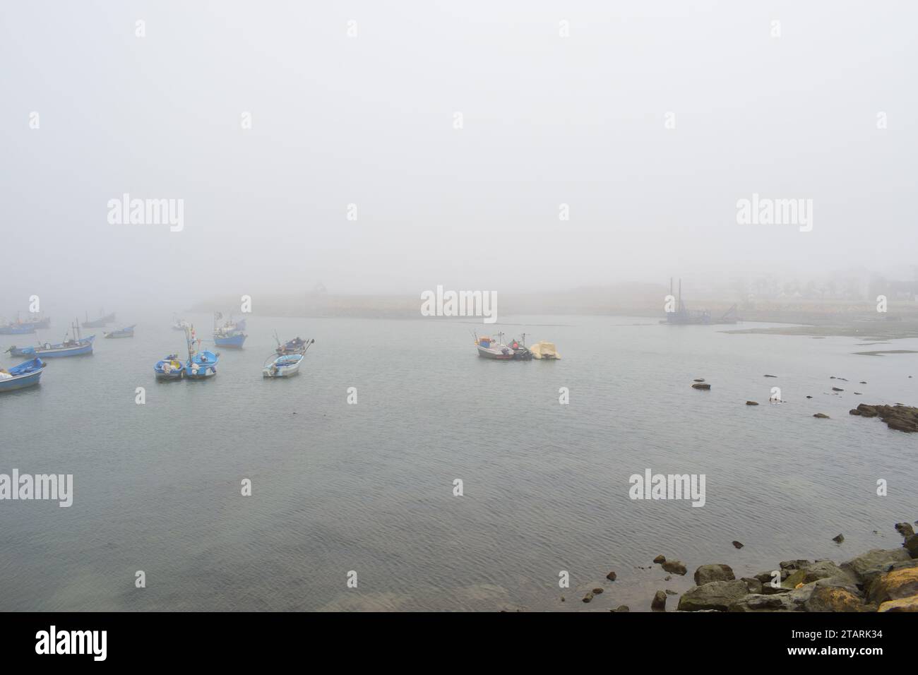 Unbearbeitetes Foto von Fischerbooten in einem Hafen bei nebeligem Wetter Stockfoto