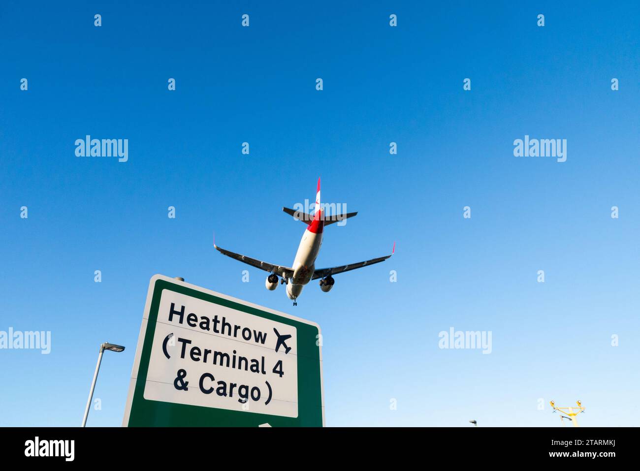 Flugzeugjet im Finale landet am Flughafen London Heathrow, Großbritannien, über Verkehrsschild mit Wegbeschreibung zum Terminal 4 und Cargo Heathrow Stockfoto