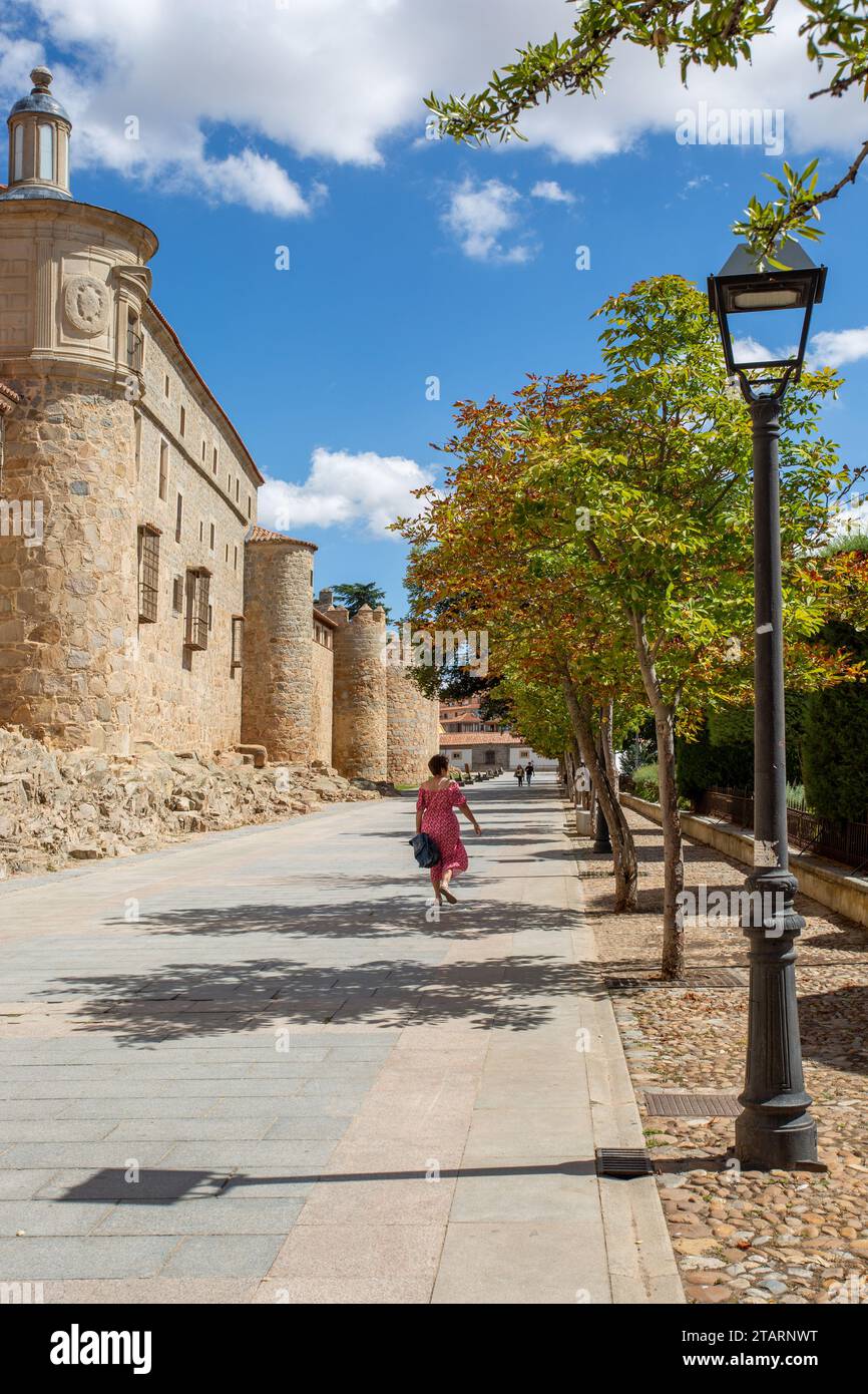 Frau, die an den Festungsmauern der spanischen Stadtmauer Avila in der autonomen Gemeinde Kastilien und León Spanien vorbeigeht Stockfoto