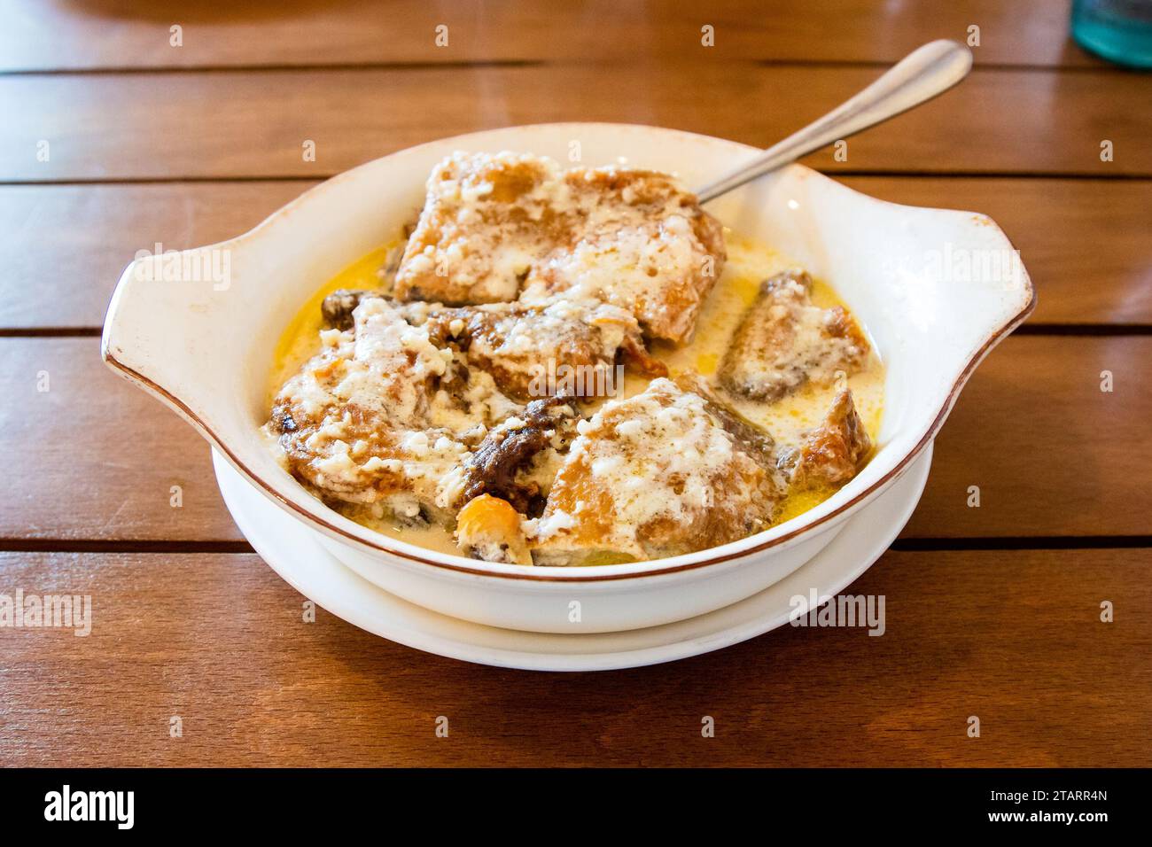 Reisen Sie nach Georgien - Portion Chkmeruli (georgisches Gericht, Hühnchenstücke in cremiger Knoblauchsoße gebraten) in einer Schüssel auf Holztisch im lokalen Café in Batumi Stockfoto