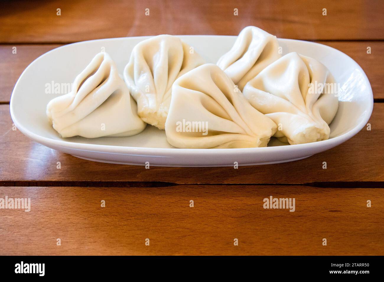 Reisen Sie nach Georgien - ein Teil des gekochten Khinkali (georgianische Knödel) auf einem Teller auf einem Holztisch im lokalen Café in Batumi Stockfoto